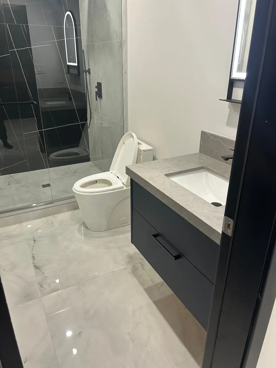 Navy floating vanity with quartz top and marble-look floor