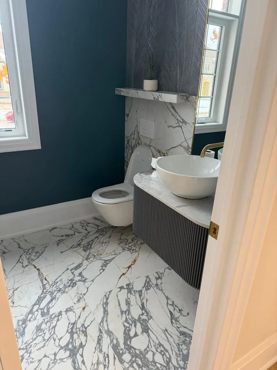 Powder room with vessel sink, wall-hung toilet and navy accent wall