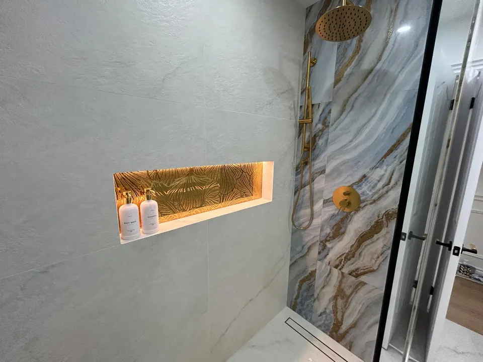 Lit shower niche with gold fixtures