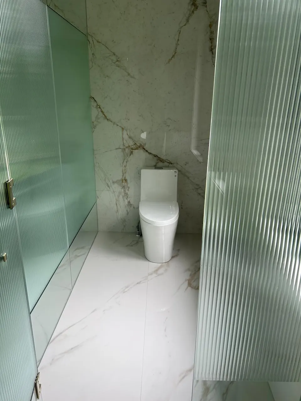 Toilet room behind a fluted glass partition