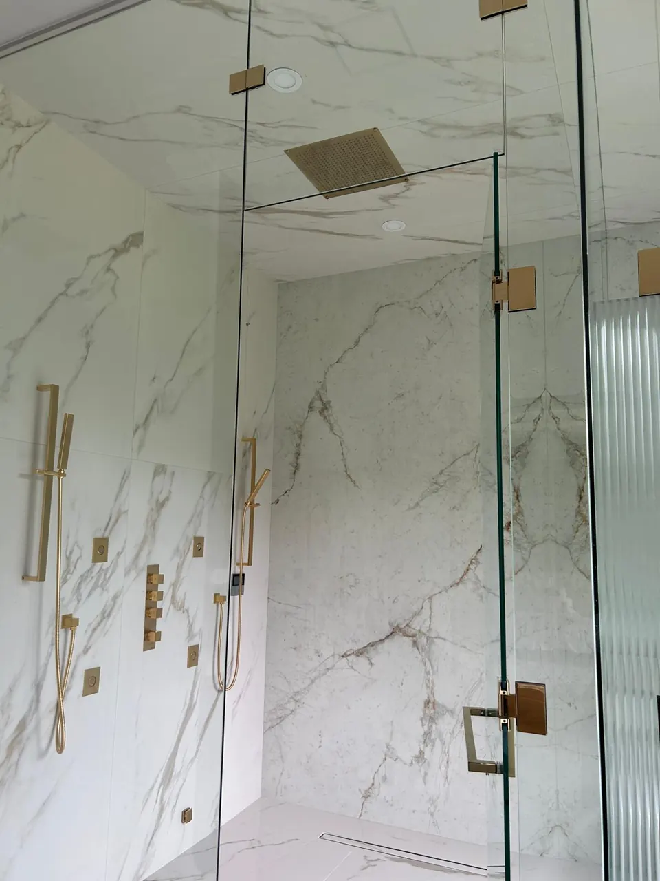 Walk-in shower with gold rain head and body sprays
